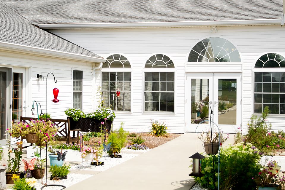A charming white house with a well-maintained garden and patio area.
