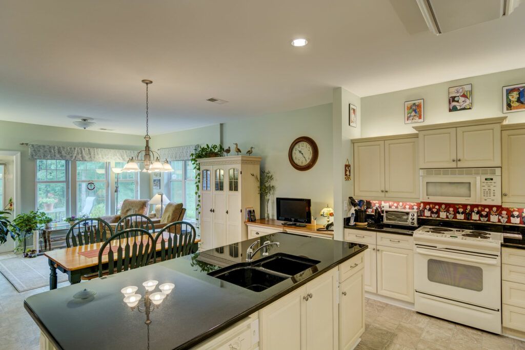 A modern open-concept kitchen with a granite island overlooking a cozy living and dining area.