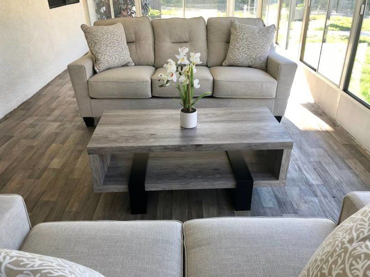 A modern living room featuring a comfortable sofa set and a stylish coffee table with a flower arrangement.