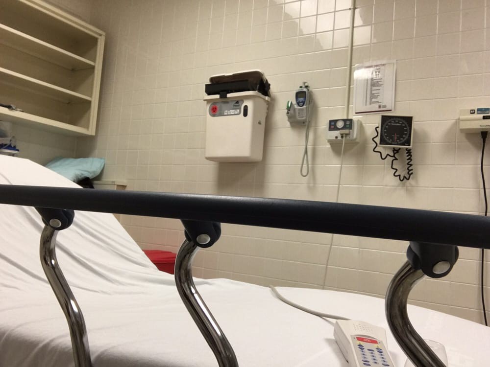 A hospital room with a bed and medical equipment on the wall.