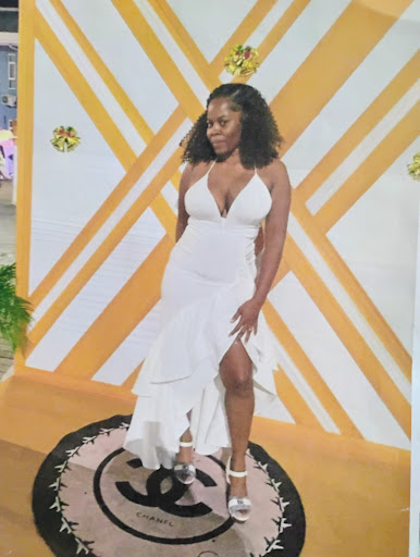 A stunning woman in a white dress poses gracefully at a stylish event.
