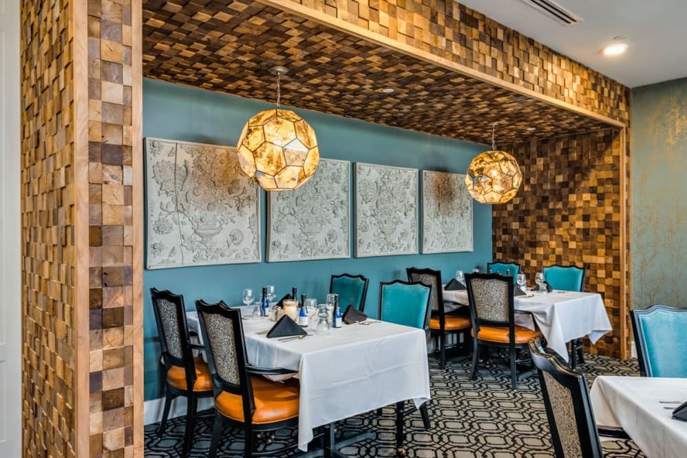 A beautifully decorated restaurant interior with neatly arranged tables, elegant chairs, and artistic lighting.