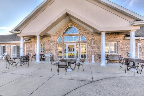 A building entrance with a patio featuring outdoor furniture and columns.