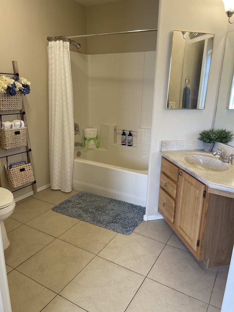 A tidy bathroom with a bathtub, sink, and storage unit.