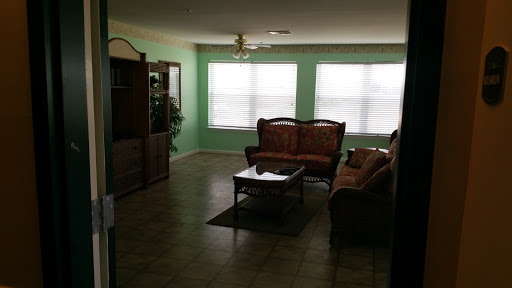 A spacious living room featuring a cozy seating area with a green color scheme.