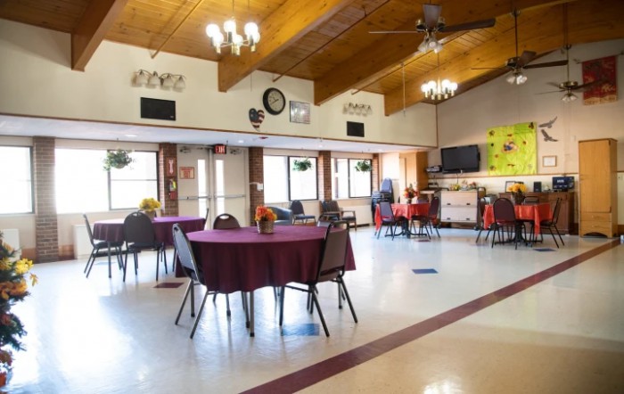 An empty dining hall with decorated tables and chairs, ideal for community gatherings.