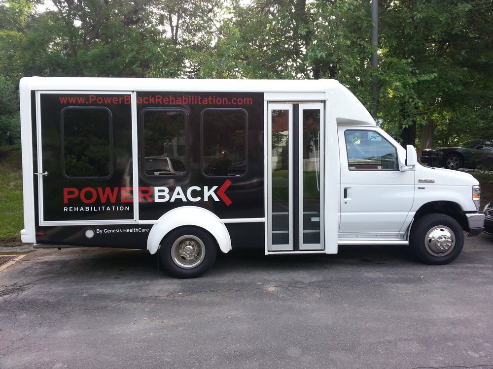 A white shuttle bus parked on a road.