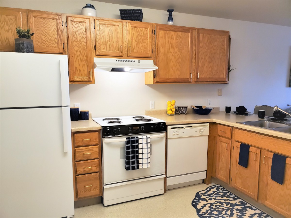 A cozy kitchen with wooden cabinets, a white refrigerator, and modern appliances.