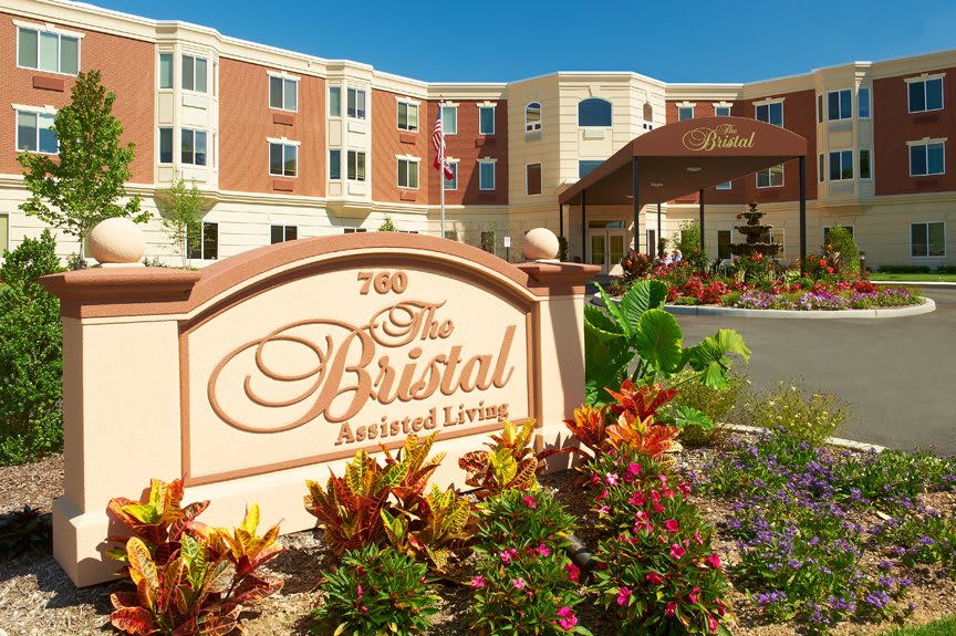 A view of an assisted living facility with landscaped gardens and clear blue skies.
