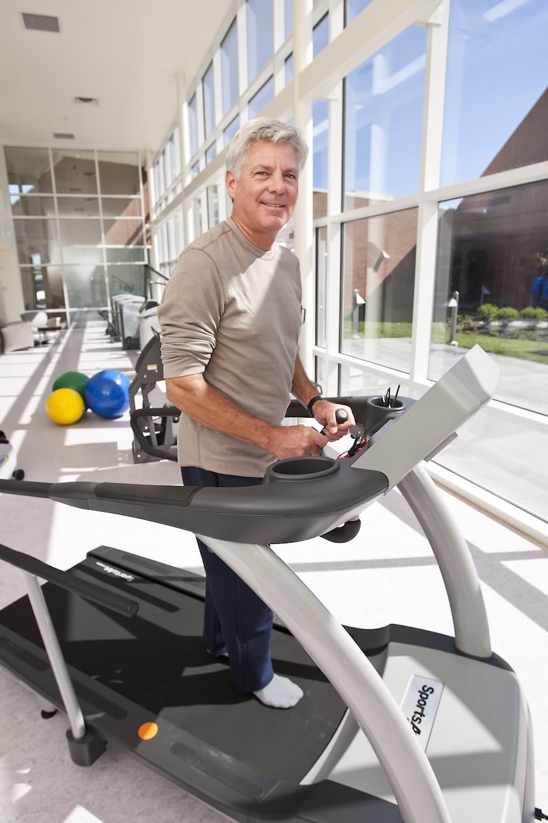 A person using a treadmill in a bright gym environment.