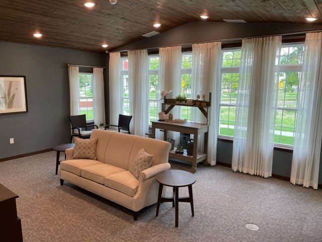 A cozy living room with a sofa, large windows, and elegant curtains.