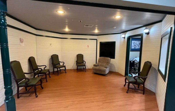 A spacious room with several chairs and a recliner arranged in a semi-circle on a wooden floor.
