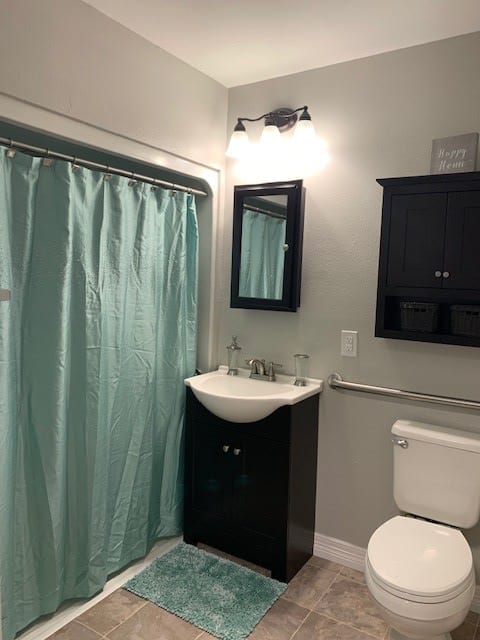 A modern bathroom with a light blue shower curtain and dark vanity.