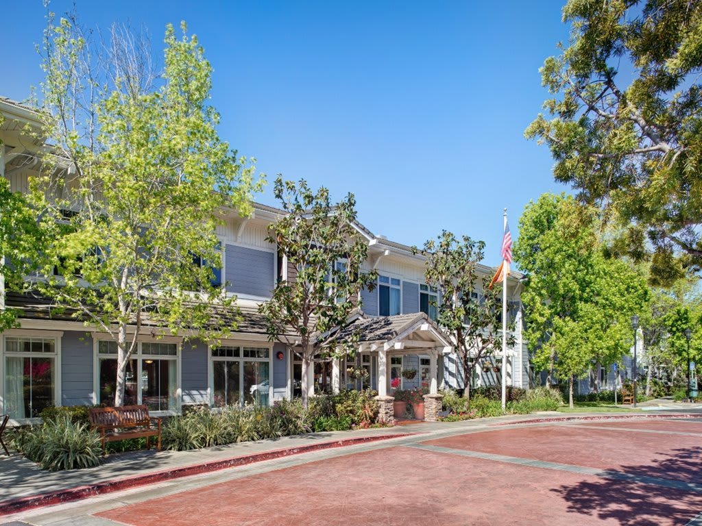 A view of a two-story building surrounded by trees under a clear blue sky.