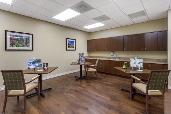 A modern meeting room with wooden flooring, furnished with tables and chairs.