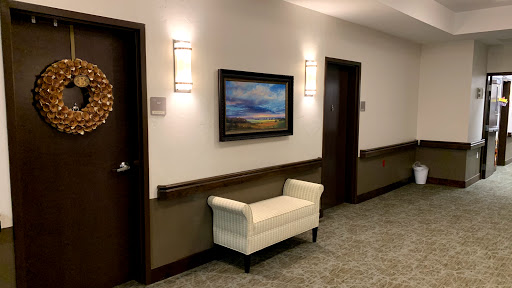 A well-lit hallway featuring a white bench, artwork on the wall, and two doors.