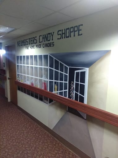 A trompe-l'oeil mural creating the illusion of a candy shop entrance in a hallway.