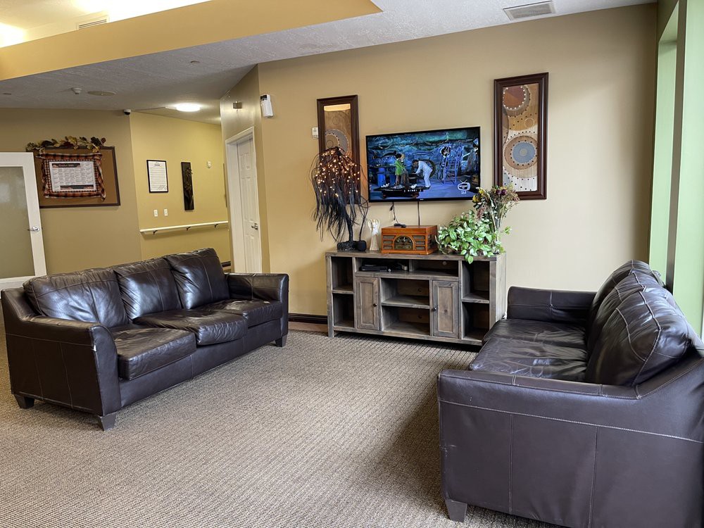 A well-furnished waiting room featuring leather sofas and a television.
