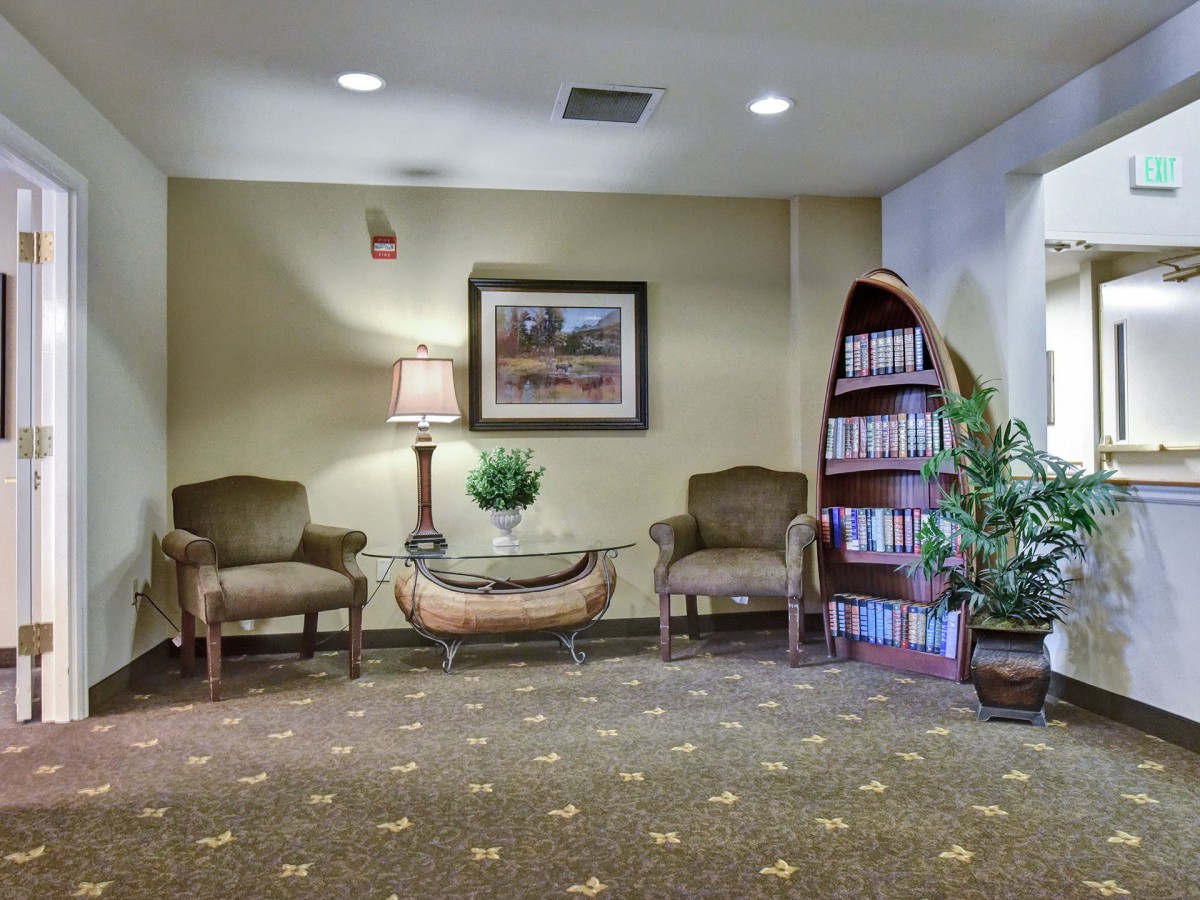 Cozy waiting area with chairs, a table, and bookshelf.