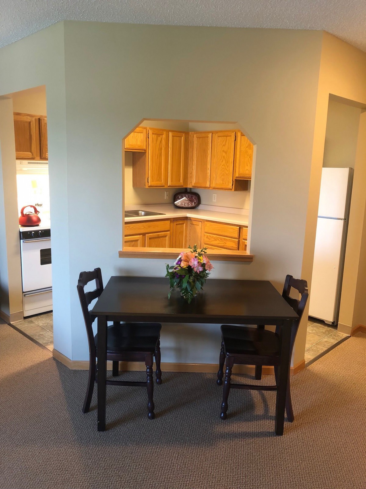 Cozy dining area with a view into the kitchen, featuring a dark wooden table and chairs.
