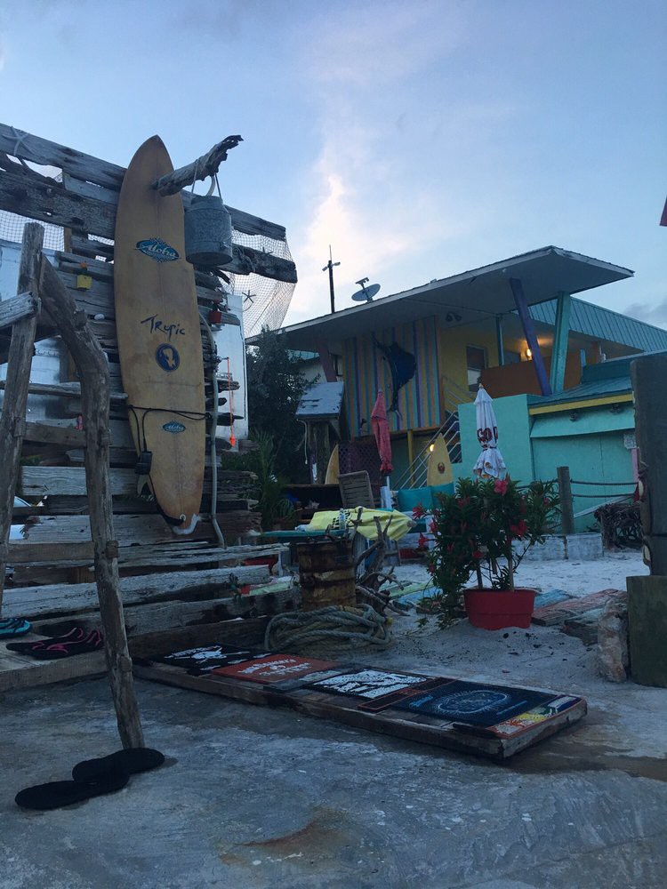 A colorful coastal building with surfboards and artwork displayed outside.