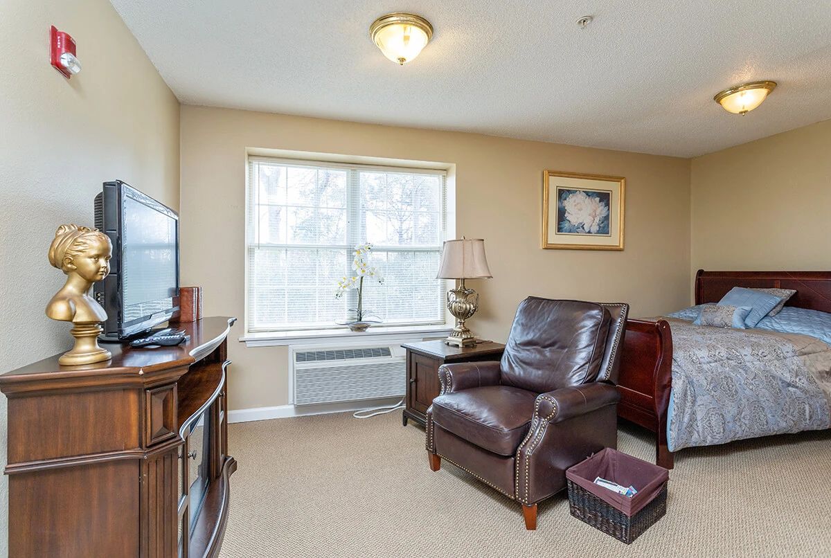 A cozy living room with a leather chair, television, and a large window letting in natural light.