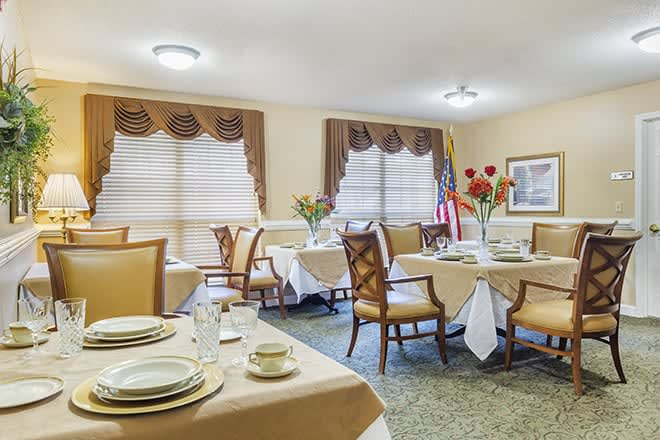 A neatly arranged dining room with tables set for a meal, featuring elegant decor and comfortable seating.