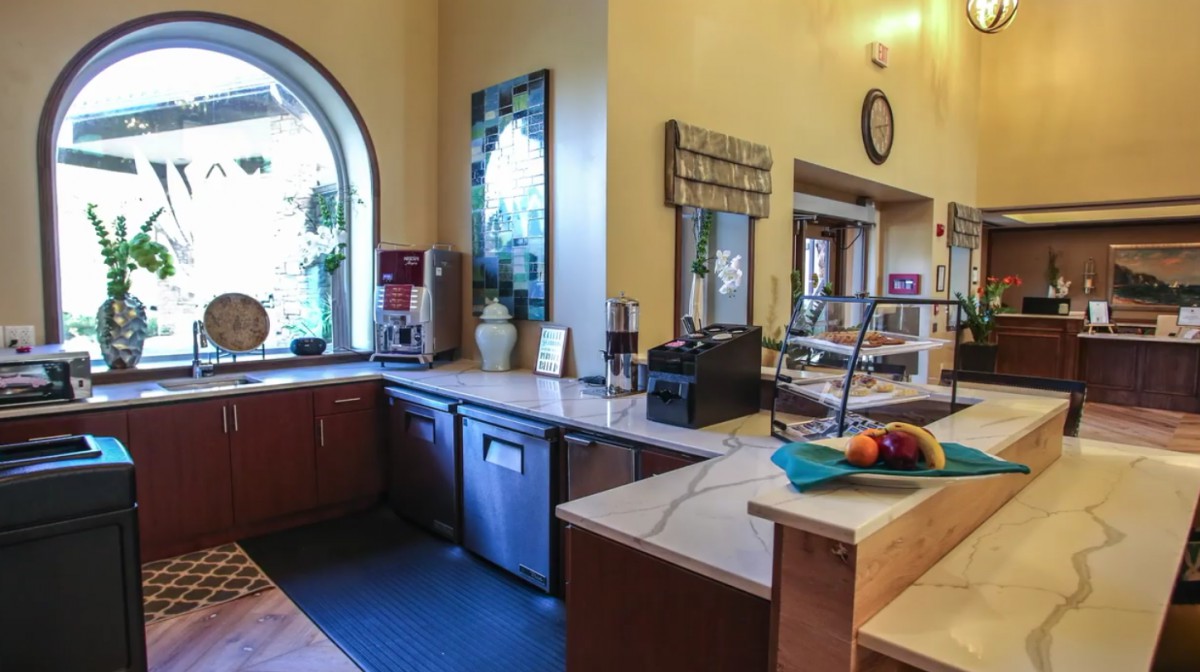A cozy kitchen with a coffee machine and serving area near a large window.