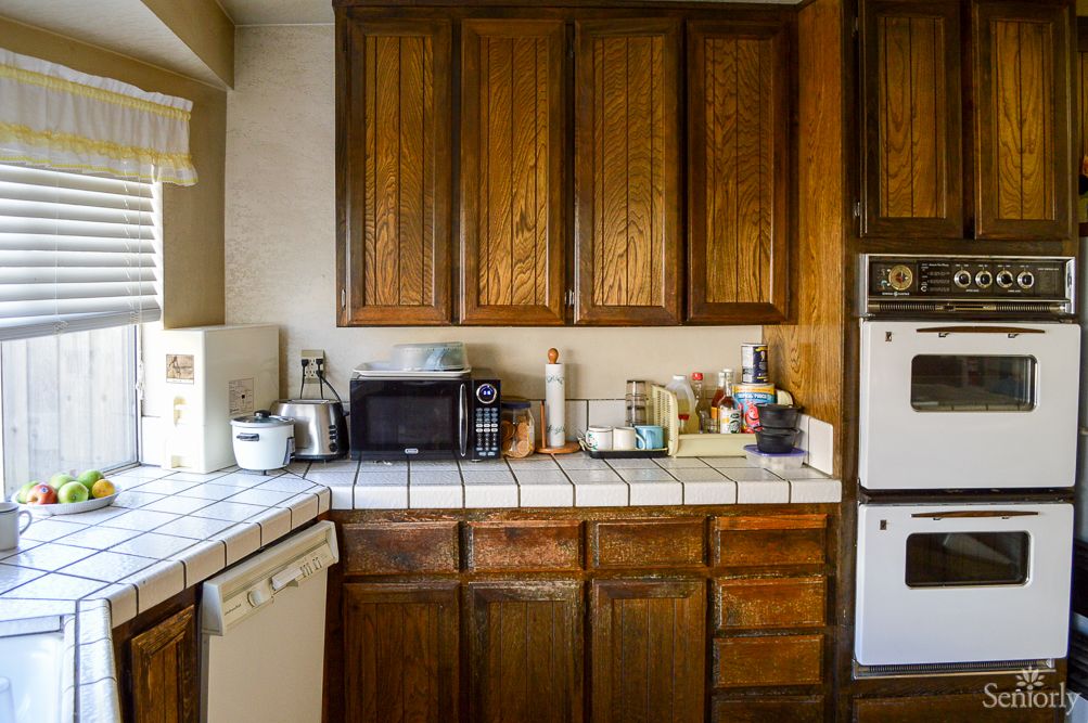 A cozy kitchen with wooden cabinets, featuring various appliances on the countertop including a microwave and toaster.