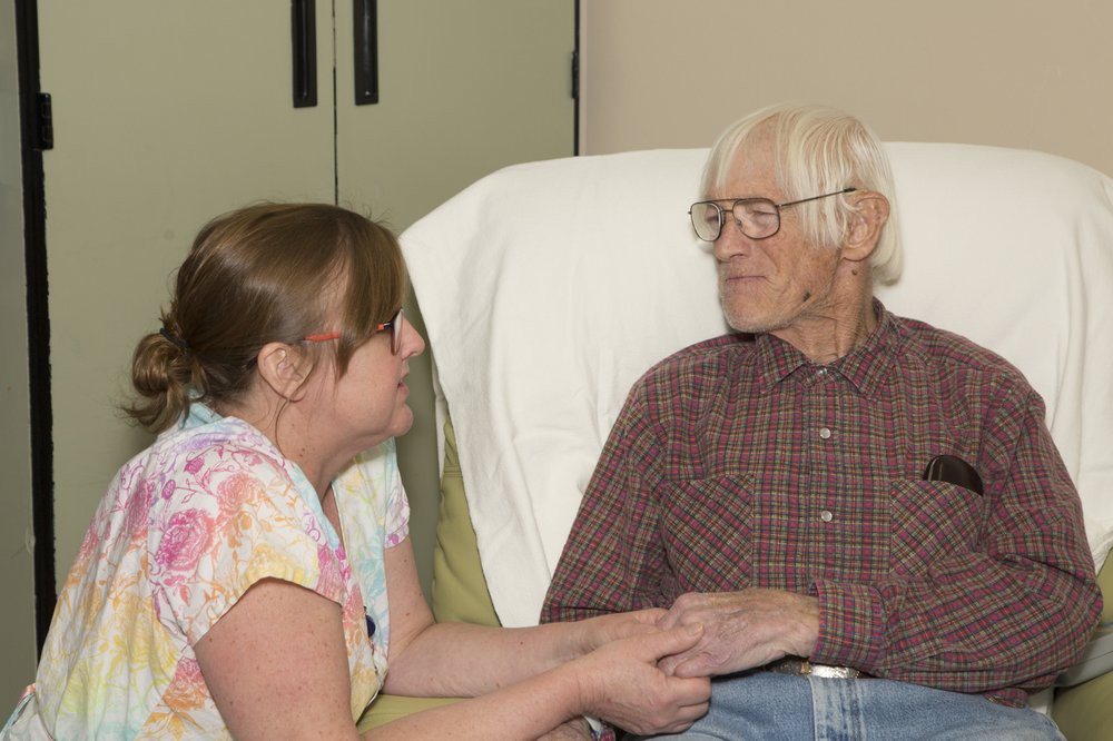 A caregiver offering support and companionship to an elderly person.