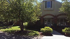 A suburban house with a well-maintained front yard and a tree casting shadows.