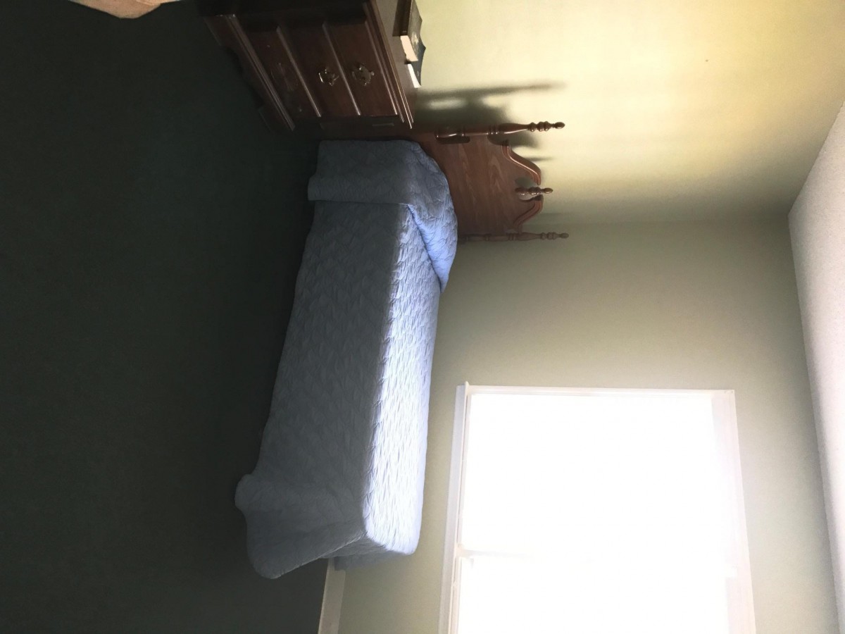 A simple bedroom with a single bed and dresser next to a window.