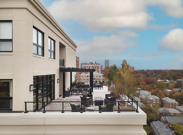 A stylish rooftop patio with a scenic city view, featuring modern furniture and a pergola.