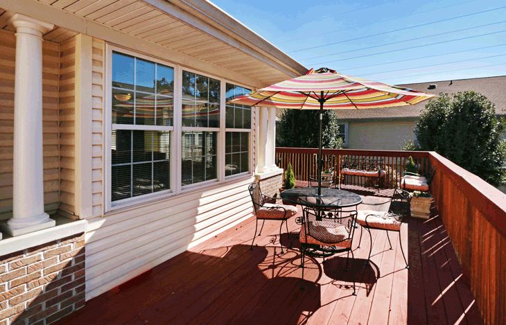 A cozy outdoor patio with a table, chairs, and an umbrella on a wooden deck.