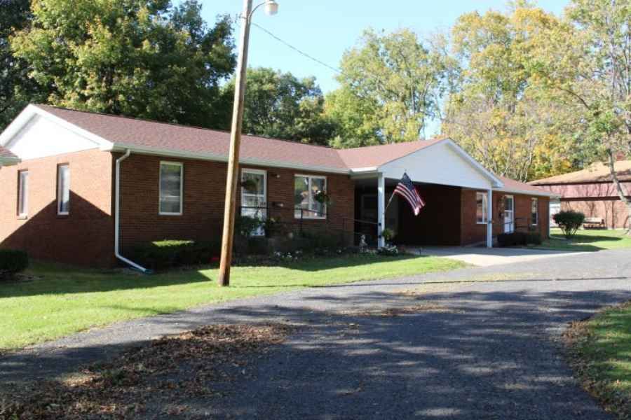 A suburban brick ranch-style house with a driveway and an American flag.