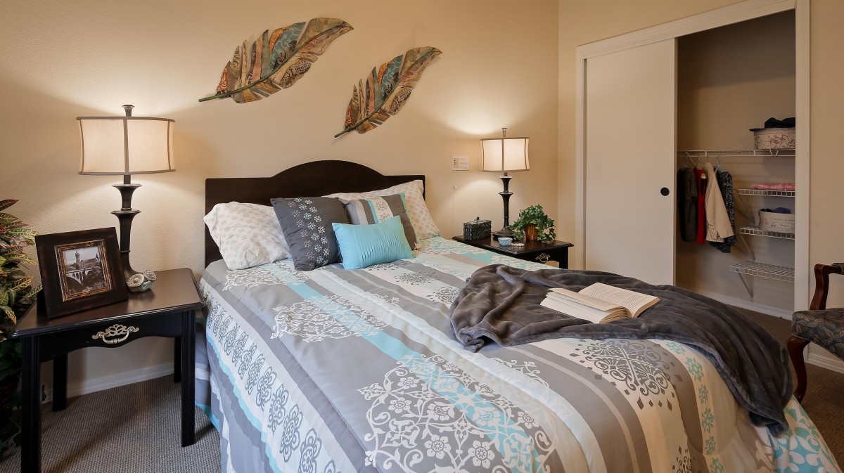A cozy bedroom featuring a neatly made bed with decorative pillows and wall art above the headboard.