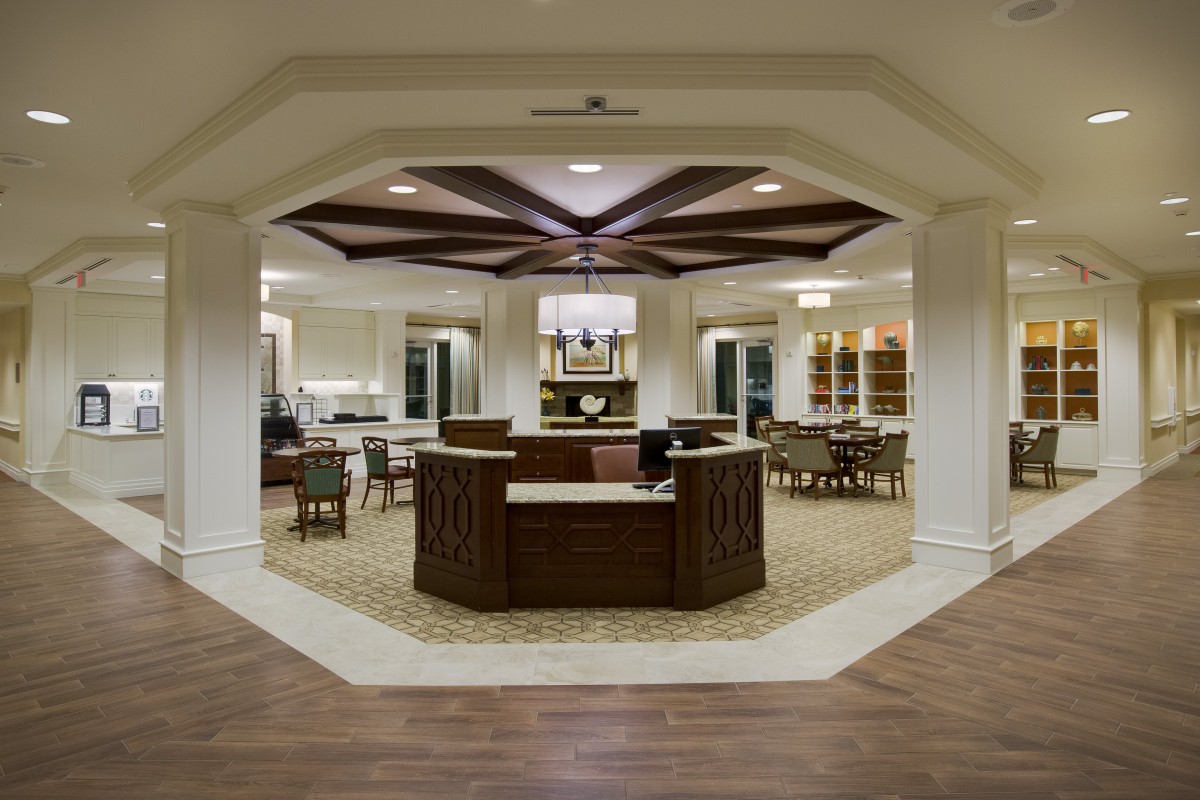A modern lobby featuring a central reception desk with elegant lighting and comfortable seating.