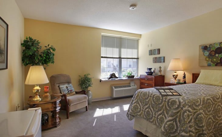 A cozy bedroom featuring a comfortable chair, well-lit interior, and tasteful decor.