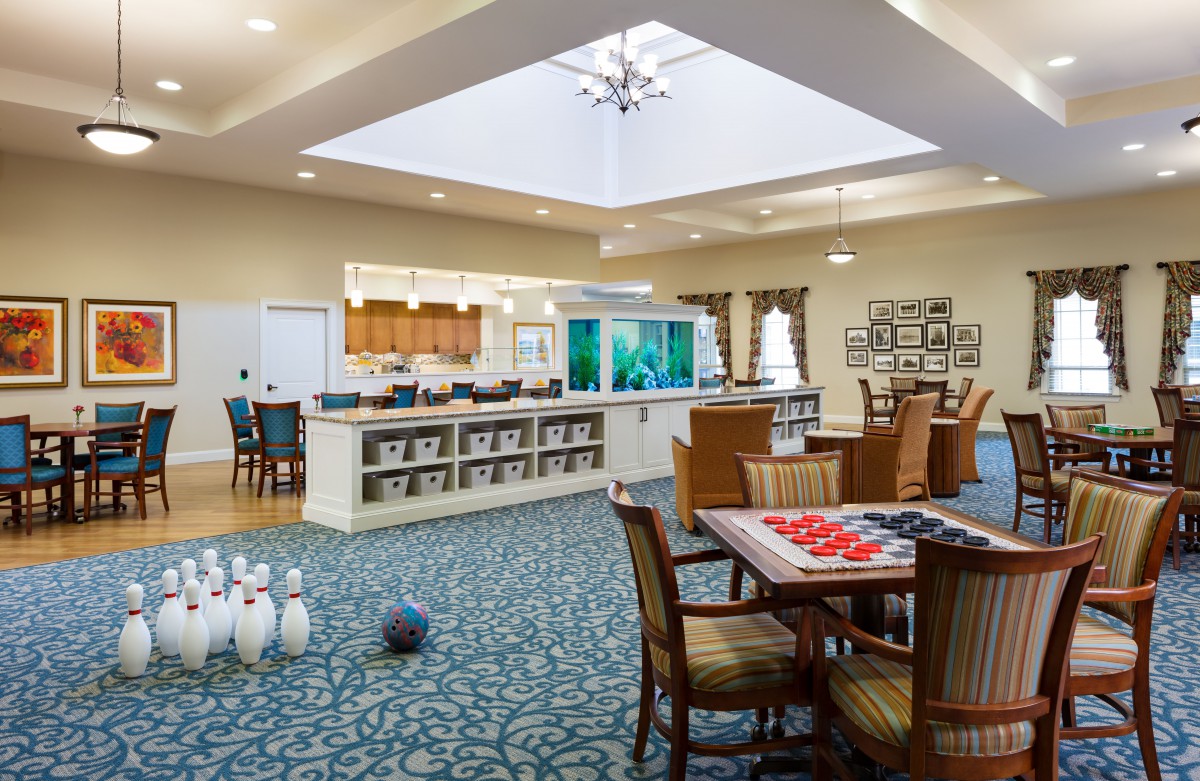 A spacious lounge featuring a mini bowling setup, seating area with tables, and an aquarium.