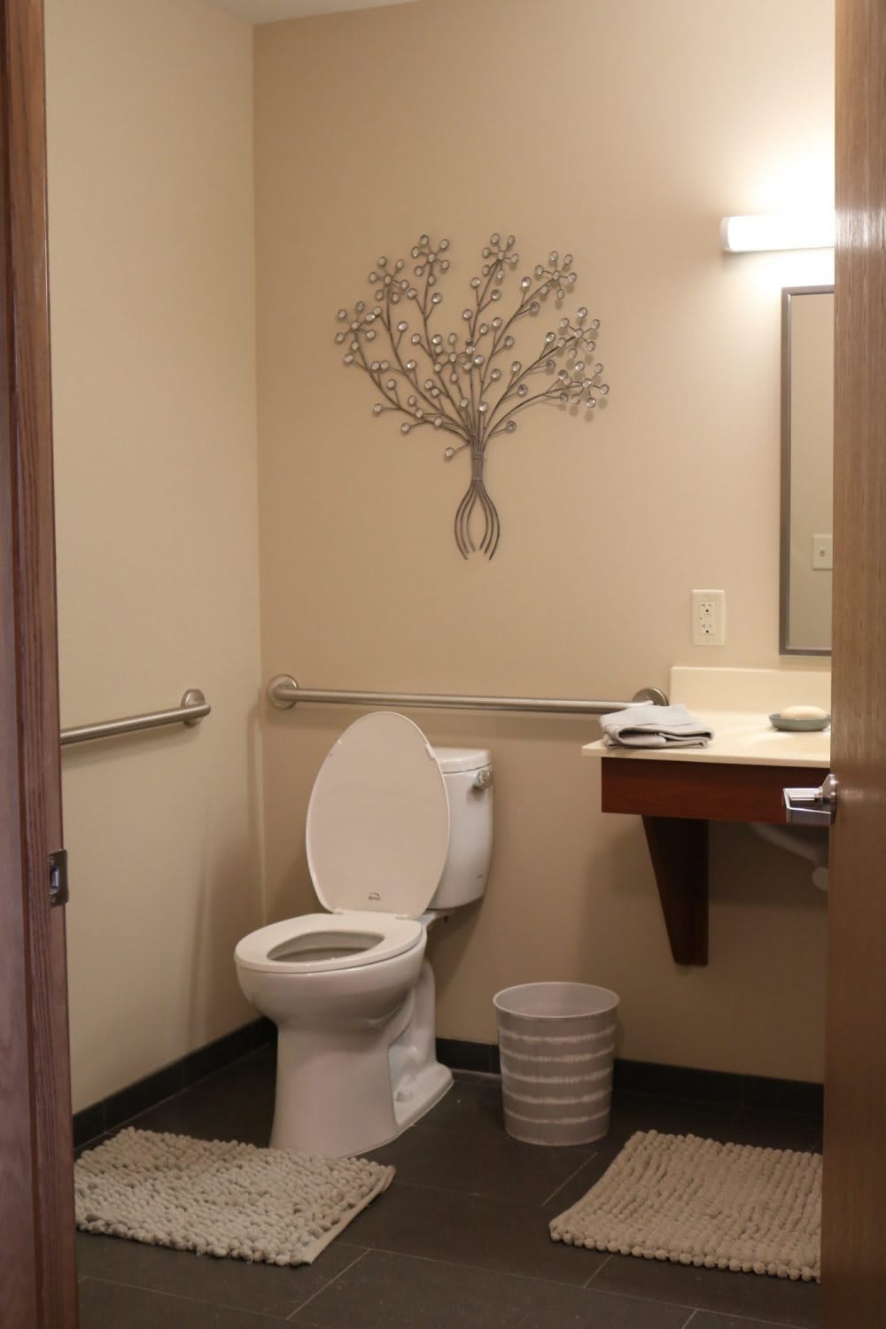 A clean bathroom with a tree wall art and essential amenities.