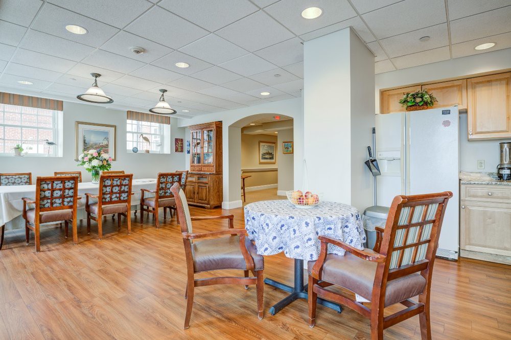 A cozy dining area with wooden floors and neatly arranged tables and chairs.