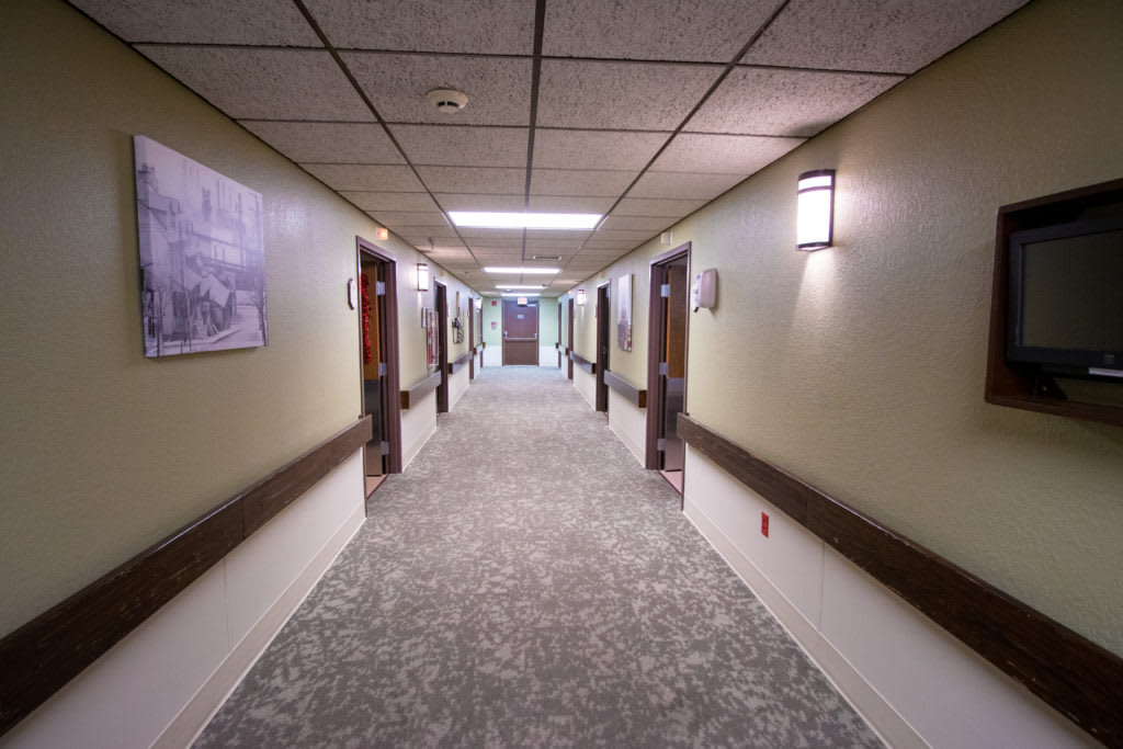 A well-lit hallway with multiple doors and carpeted flooring.