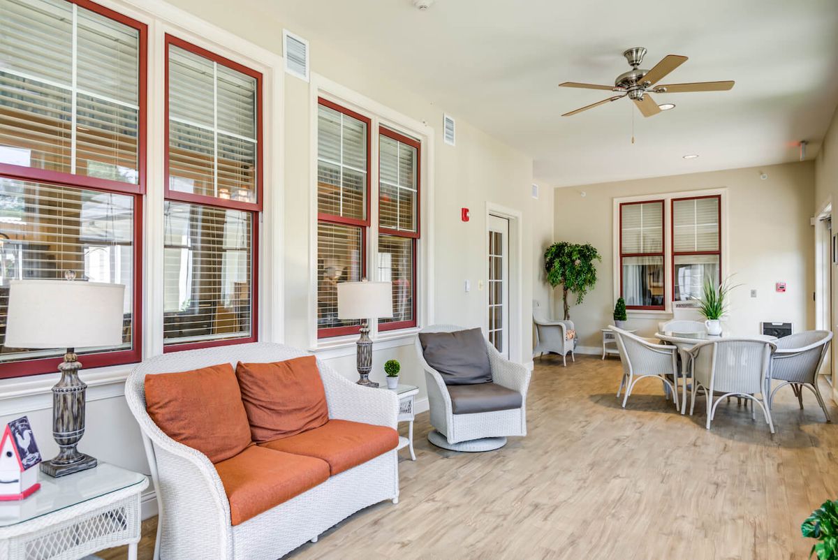 A spacious living area with comfortable seating, a dining table, and a ceiling fan.