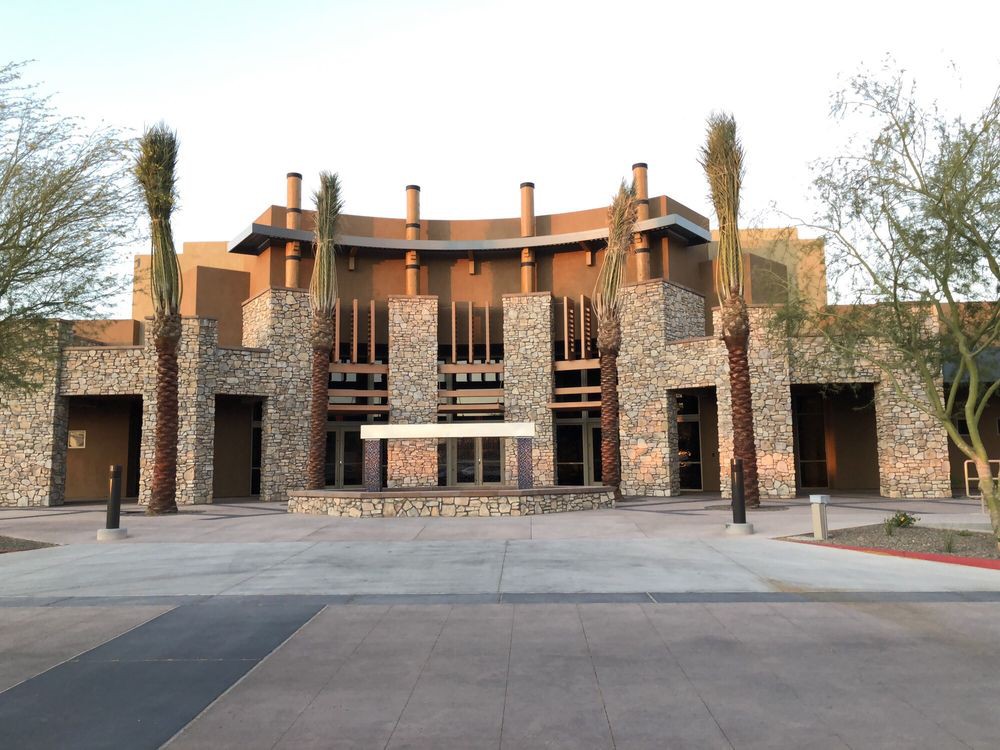 A modern building with a stone facade and palm trees at the entrance.