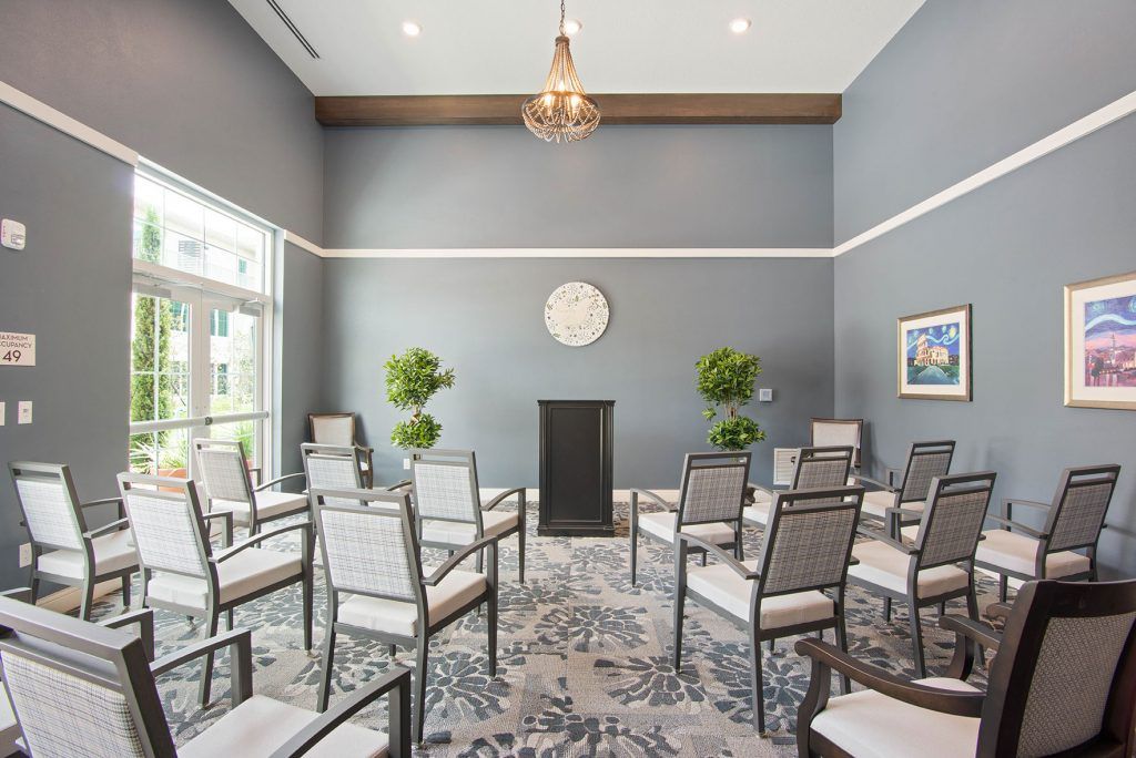 A modern conference room with neatly arranged chairs and indoor plants, featuring neutral color tones.
