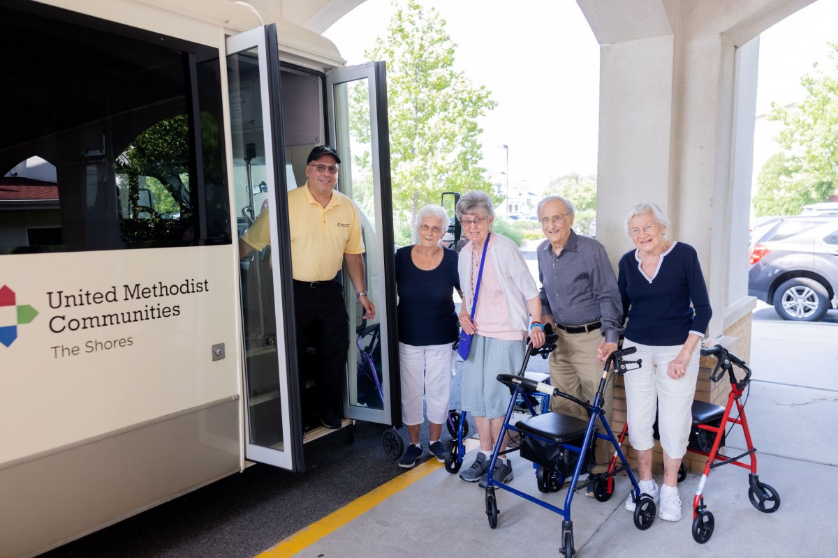 A group of elderly people standing in front of a bus.