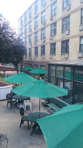 A serene outdoor seating area with green umbrellas and tables, situated next to a building.