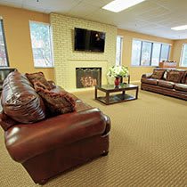 A cozy living room with leather sofas, a fireplace, and a mounted television.