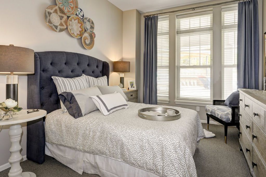 A stylish bedroom with a tufted headboard, multiple pillows, and decorative elements on the walls.