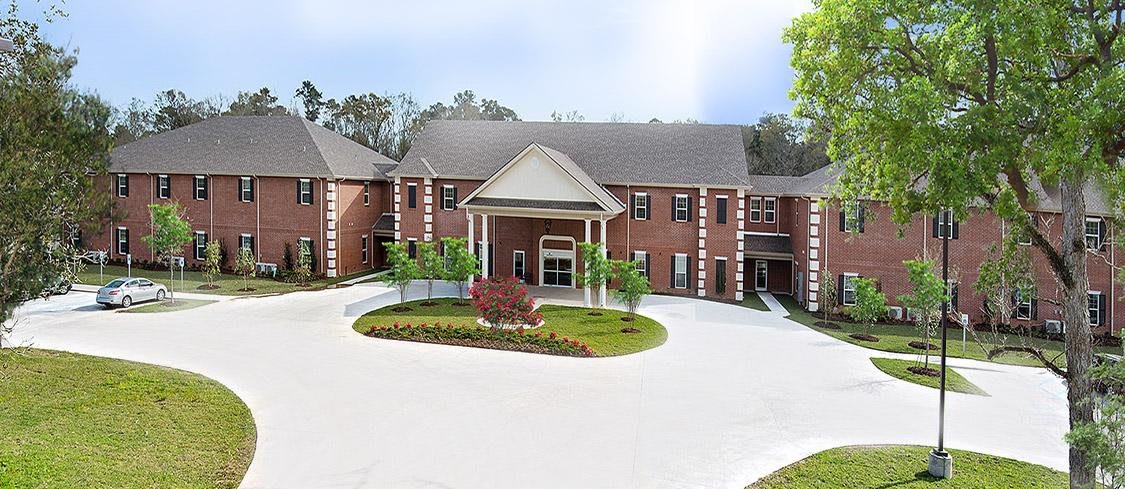 A large, brick building with a landscaped entrance and circular driveway.